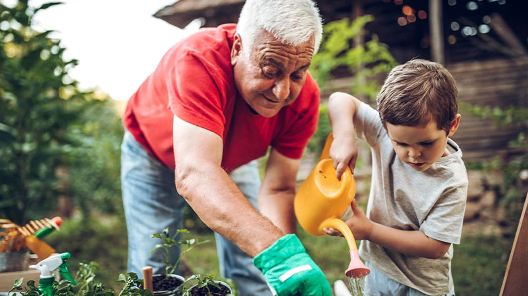 Young boy and father watering the garden